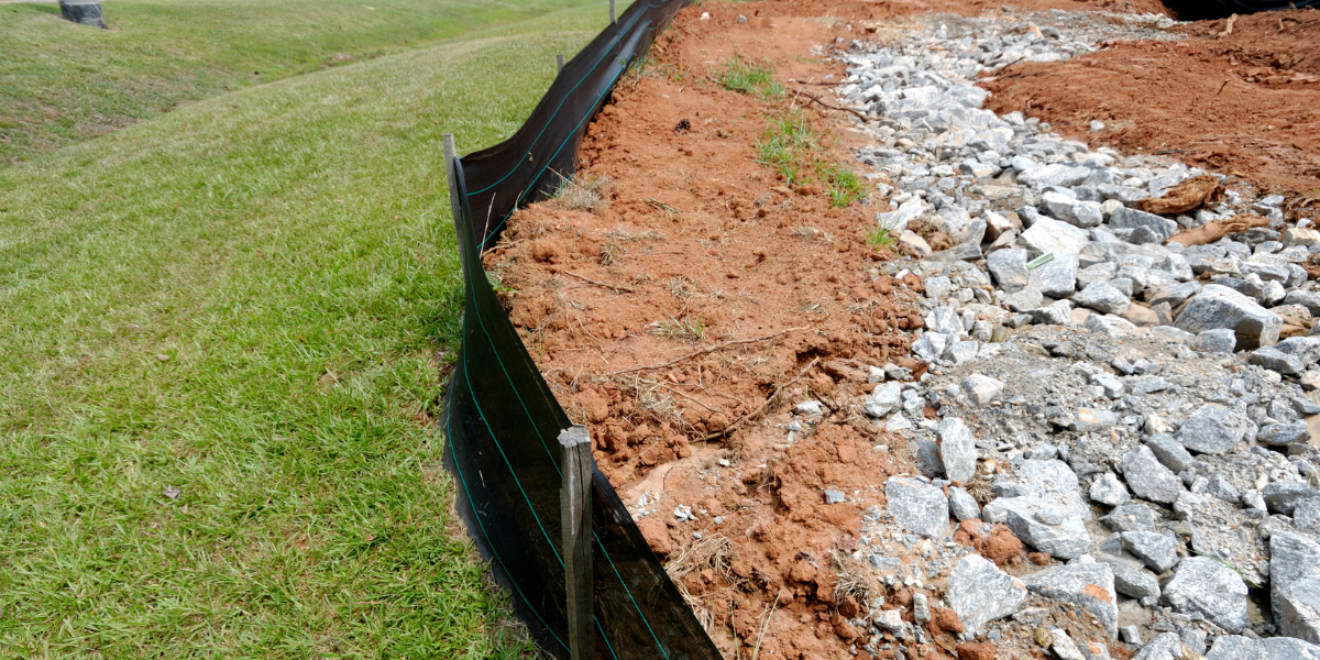 black barrier, containing dirt and gravel, preventing spillage into green grassy area